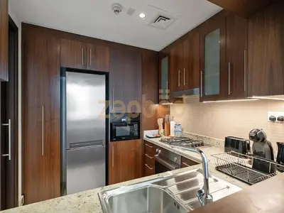 a kitchen with wooden cabinets and a stainless steel refrigerator at Zapbed House Luxury 2BR at Boulevard Point Walk to Dubai Mall in Dubai