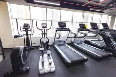 a gym with several treadmills in a row at Maison Privee - Comfortable Downtown Apartment with City Skyline Vws in Dubai