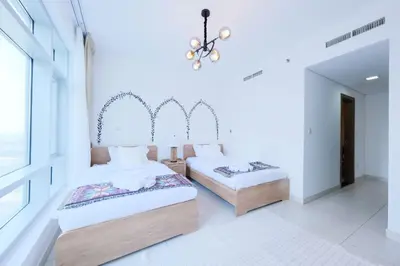 two beds in a room with white walls and a chandelier at Premium Burj Khalifa View Downtown Dubai in Dubai