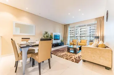 a dining room and living room with a table and chairs at Prime Waterfront Living, Just Moments from Marine Transport, Bus Stops, and Dubai Water Canal, Waters Edge, Business Bay by Deluxe Holiday Homes in Dubai