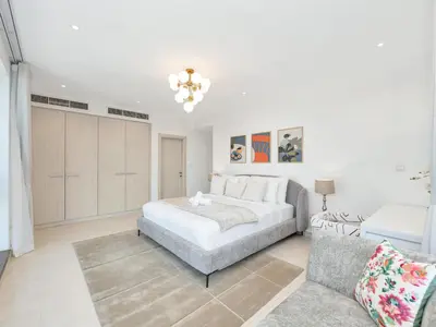 a white bedroom with a bed and a couch at Kensington-2BR Huge & Central at Executive Tower in Dubai