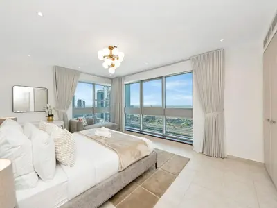 a bedroom with a large bed and large windows at Kensington-2BR Huge & Central at Executive Tower in Dubai