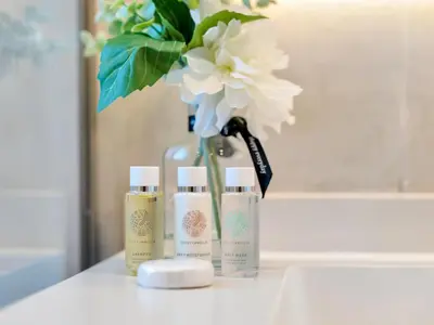 a vase with a flower and three products on a counter at Kensington-2BR Huge & Central at Executive Tower in Dubai