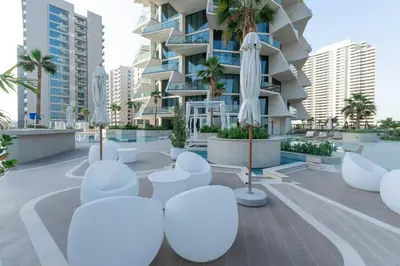 a view of a building with white chairs and umbrellas at The Royale Blue Luxury Suite 325 Private Plunge Pool in Dubai