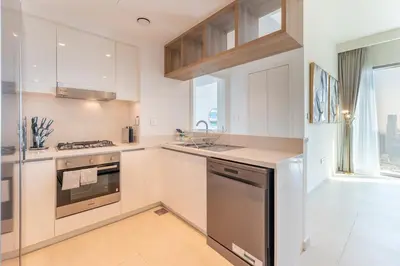 a white kitchen with a stove and a sink at Stylish 2BHK with Burj Khalifa Views in Downtown in Dubai