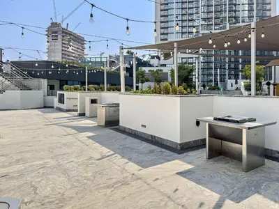 a rooftop patio with tables and benches and buildings at Chic 1BR Retreat Sobha Crest with Pool & Gym in Dubai