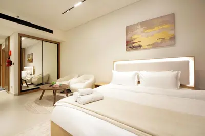 a bedroom with a large white bed and a living room at Wecation - Cozy Studio , Trillionaire , Private Jacuzzi in Dubai