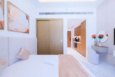 a white bedroom with a bed and a kitchen at Modern Studio Azizi Riviera 59 Al Merkadh Community in Dubai