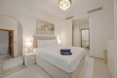 a white bedroom with a large bed and a bathroom at Daniels 2BR Duplex at Central Park Tower, DIFC in Dubai