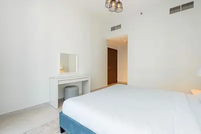 a white bedroom with a bed and a table at CitiHome - Spacious 2BR - Park Gate Residences in Dubai