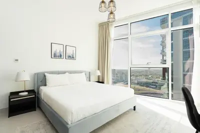 a white bedroom with a bed and a large window at CitiHome - Spacious 2BR - Park Gate Residences in Dubai