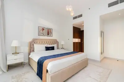 a white bedroom with a large bed and a chandelier at CitiHome - Spacious 1BR - Park Gate Residences in Dubai