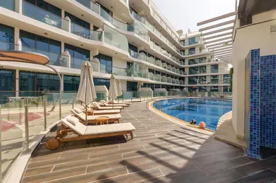 a building with a swimming pool and lounge chairs and a hotel at Luxury 2BR with Private Pool Balcony Arjan in Dubai