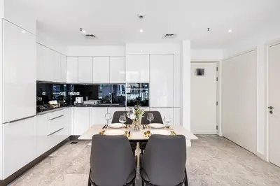 a white kitchen with a table and chairs at Stylish Apartment Business Bay Prime Location in Dubai