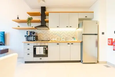 a kitchen with white cabinets and a refrigerator at Steps from Dubai Hills Mall, Near Scenic Park, and Easily Connected to Dubai Top Attractions - Socio Tower 1, Dubai Hills by Deluxe Holiday Homes in Dubai