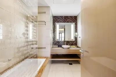 a bathroom with a tub and a sink and a mirror at Stylish 1-Bedroom Apartment at DAMAC Paramount in Dubai