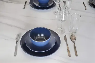 a table with a blue bowl and plates and silverware at Incredible Family Townhouse Villa I Sleeps 10 in Dubai