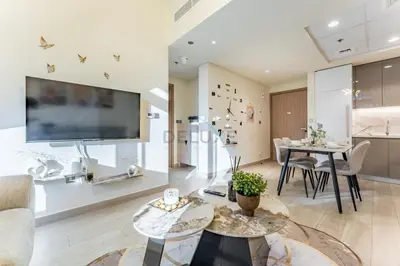 a living room with two tables and a tv at Cozy 1BR, Easy Access to Dubai Mall - Azizi Riviera 36 by Deluxe Holiday Homes in Dubai