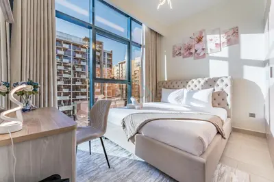 a bedroom with a bed and a desk and a window at Cozy 1BR, Easy Access to Dubai Mall - Azizi Riviera 36 by Deluxe Holiday Homes in Dubai