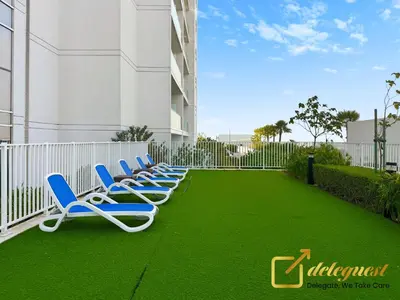 a row of lounge chairs on a lawn in front of a building at Modern Comfort Studio DAMAC Hills 1 in Dubai