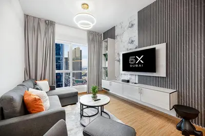 a living room with a couch and a tv on a wall at FiveX Luxury 2BR at Lake Point JLT in Dubai