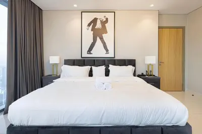 a bedroom with a large white bed with two towels at Luxe 3BR with Infinity Pool and Burj Khalifa View l High Floor in Dubai