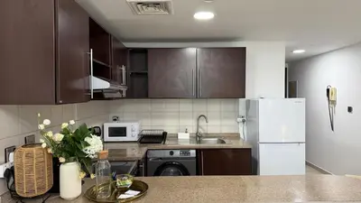 a kitchen with brown cabinets and a white refrigerator at Huge Studio DMCC Metro Close to Marina in Dubai