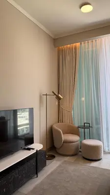 a living room with a bed and a chair and a television at Stunning Brand New Stylish Studio in JVC in Dubai