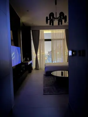 a dark room with a bed and a large window at HYDE WALK STUDiO BURj ViEW & PREMiUM COMFORt in Dubai