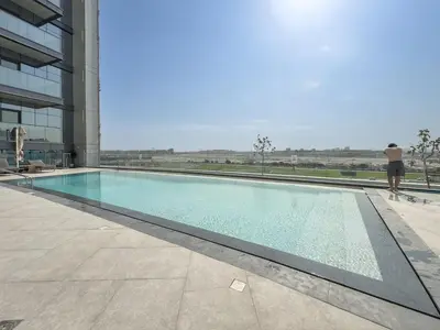 a man standing next to a swimming pool in a building at Premium 1BHK Apartment Nobles Tower by Czechin in Dubai