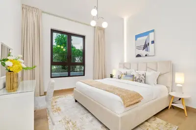 a white bedroom with a large bed and a window at Seaside 1-Bedroom Apartment with Beach Access at Port De La Mer in Dubai