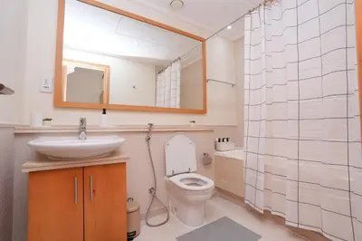 a bathroom with a toilet and a sink and a mirror at Bright 1BR Marina Promenade Partial Sea View in Dubai