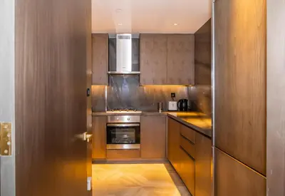 a kitchen with stainless steel appliances and wooden cabinets at New Arabian Five Palm Residences in Dubai