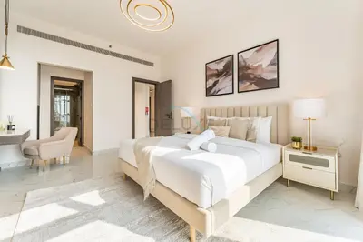 a white bedroom with a large bed and a desk at Perfectly Positioned Near Dubai Miracle Garden and Butterfly Garden, Quick Drive to Global Village, Adhara Star, Arjan by Deluxe Holiday Homes in Dubai