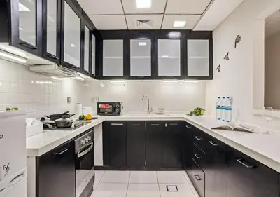 a kitchen with black cabinets and white appliances at Two Bedroom Apartment at JBR with Marina and Bluewaters Views in Dubai