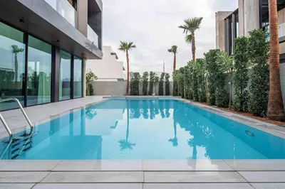 a swimming pool in front of a building with palm trees at Frank Porter - Villa La Mer, Jumeirah 1 in Dubai