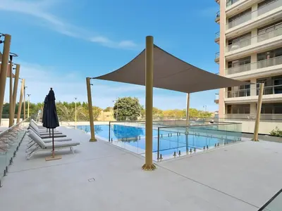 a large umbrella on a patio next to a swimming pool at Brand New 1BR Apartment In Amalia Residences Al Furjan in Dubai