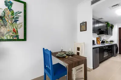 a kitchen with a wooden table and a blue chair at Waves - Nature-Inspired Studio - JLT Skyline Living in Dubai