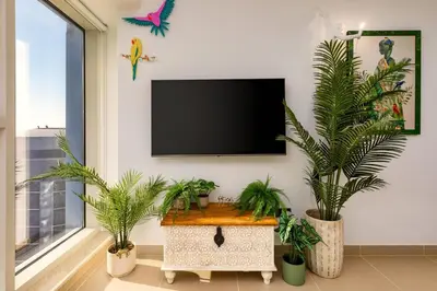 a living room with palm trees and a flat screen tv at Waves - Nature-Inspired Studio - JLT Skyline Living in Dubai