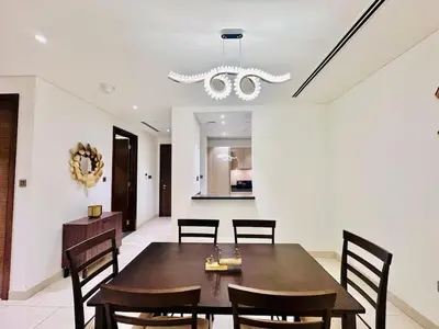 a dining room with a table and chairs and a chandelier at Greens Community View Spacious 1BR Fully Furnished in Dubai