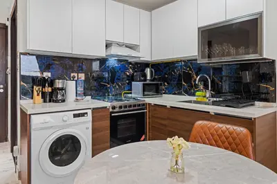 a kitchen with a washing machine and a table at Stylish Pool-View Studio w Balcony & King Bed in Dubai