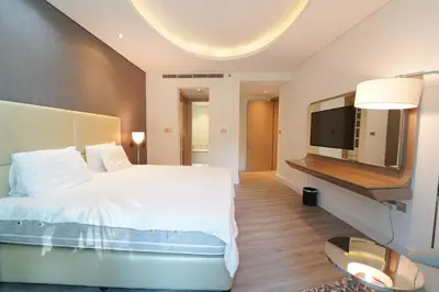 a bedroom with a white bed and a flat screen tv at Stylish 2BR Paramount Tower D in Dubai