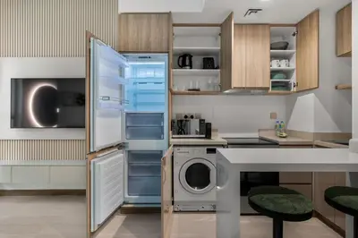 a kitchen with a refrigerator and a washer and dryer at Stylish Missoni Studio With Direct Pool Access in Dubai