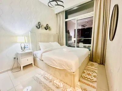 a bedroom with a large white bed and a window at 01BR apartment in DAMAC Vera Residences in Dubai