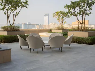 a table and chairs on a patio with trees at Marina Beachfront Oasis Infinity Pool & Modern Comfort in Dubai