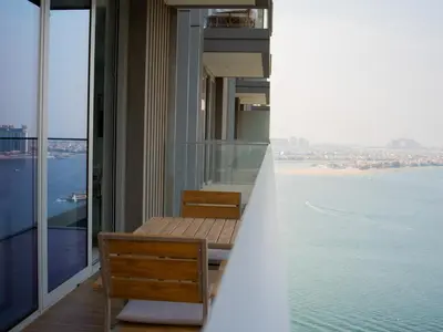a balcony with a table and chairs and the ocean at Marina Beachfront Oasis Infinity Pool & Modern Comfort in Dubai