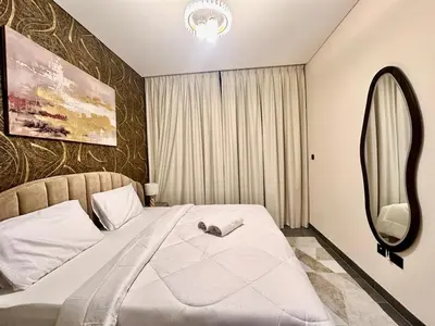 a bedroom with a large white bed with a mirror at Modern Fully Furnished 1BR plus Study in Crest Tower B in Dubai