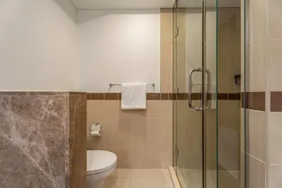 a bathroom with a toilet and a glass shower at GuestReady - Downtown stay | 29 Boulevard in Dubai