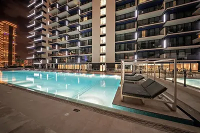 a large swimming pool with chairs in front of a building at FIRST CLASS 1BR Urban Living Comfort in Dubai