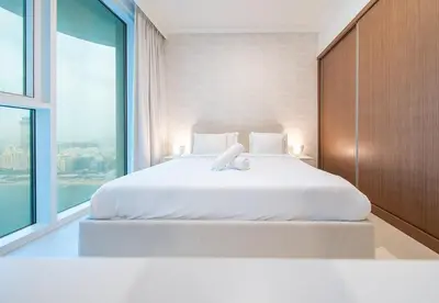 a bedroom with a white bed with a large window at 1 Bed in Palace Beach Residence with sea view in Dubai
